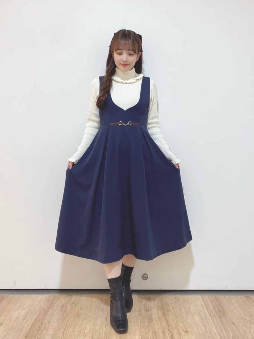 ホワイト系のニット/セーター、ブルー系のジャンパースカートを着用したレディースの冬コーディネートの1枚目の写真