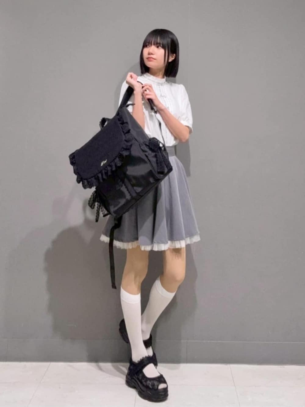 グレー系のスカート、ホワイト系のシャツ/ブラウス、ブラック系のサンダルを着用したレディースの春コーディネートの1枚目の写真