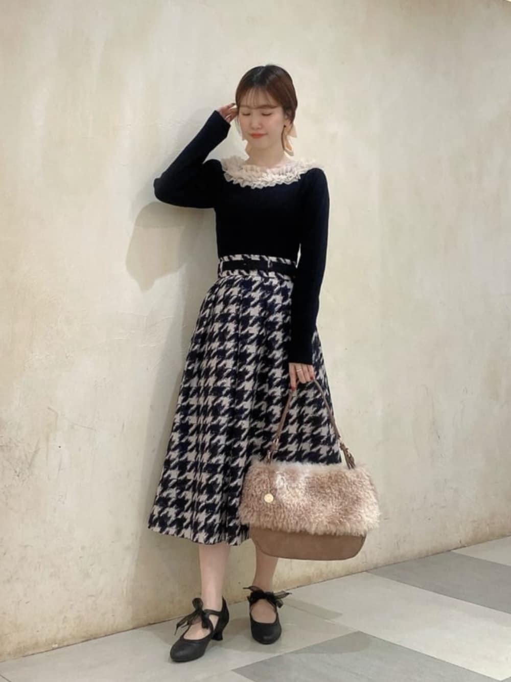 ブラック系のパンプス、ベージュ系のスカート、ブラック系のニット/セーターを着用したレディースの秋コーディネートの1枚目の写真