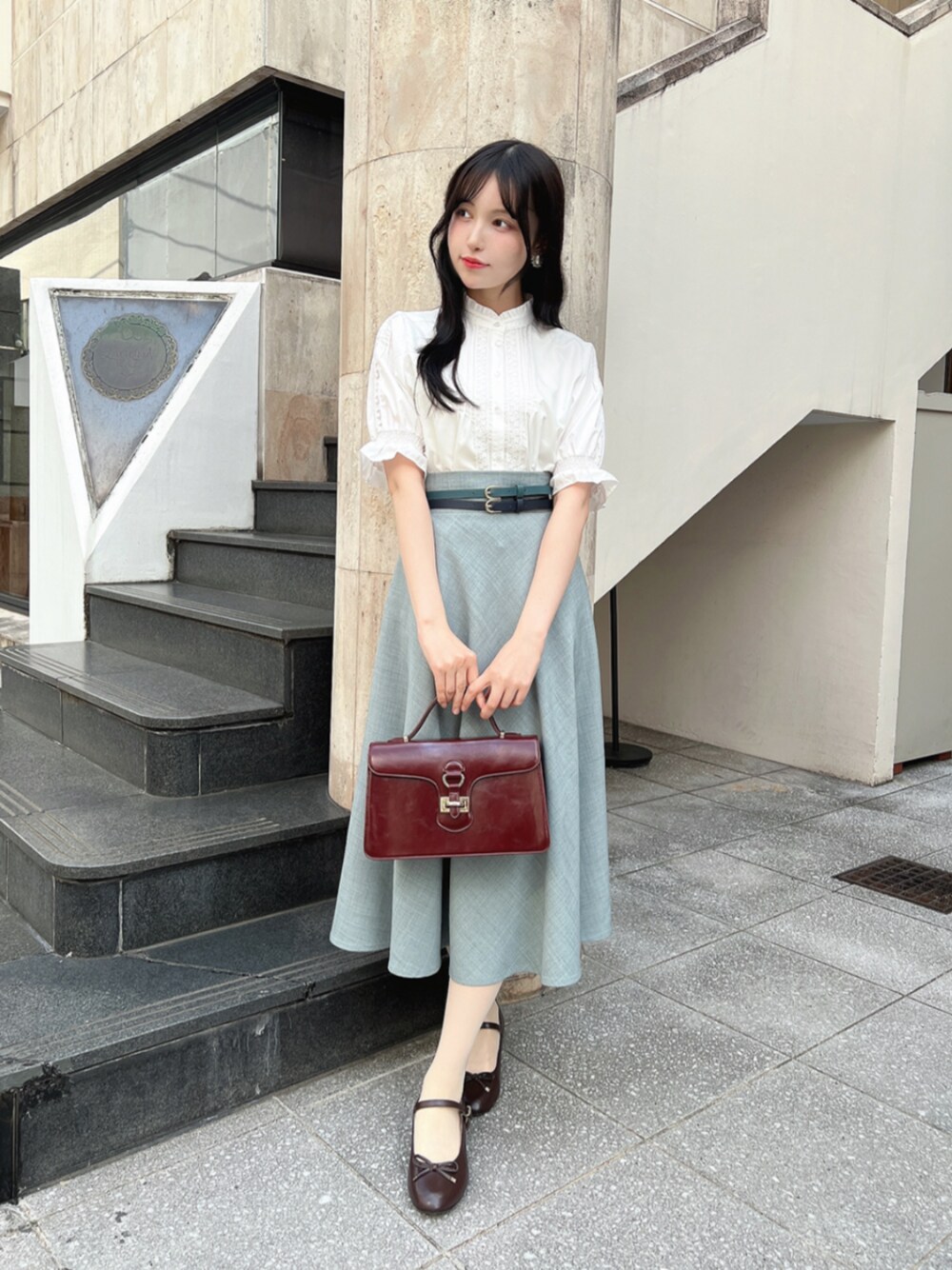 ブラウン系のパンプス、ホワイト系のシャツ/ブラウス、ブルー系のスカートを着用したレディースの春コーディネートの1枚目の写真