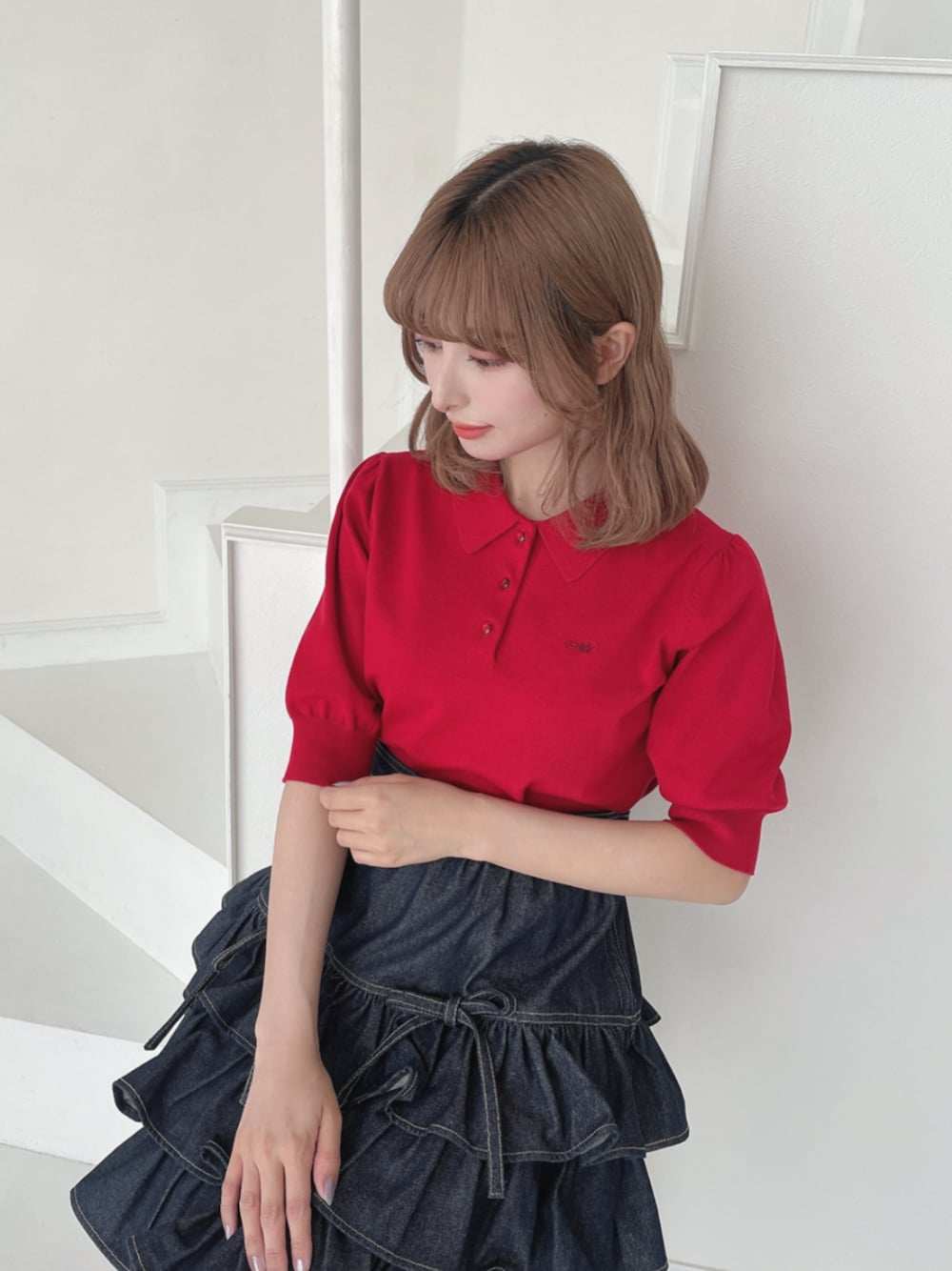 レッド系のポロシャツ、ブラウン系のローファー、ブルー系のスカートを着用したレディースの夏コーディネートの1枚目の写真