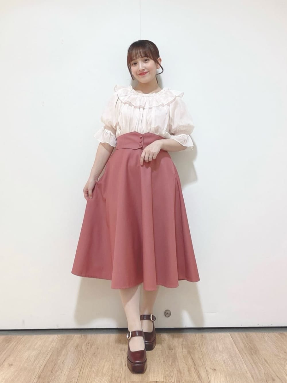 ピンク系のスカート、ブラウン系のパンプス、ピンク系のシャツ/ブラウスを着用したレディースの夏コーディネートの1枚目の写真