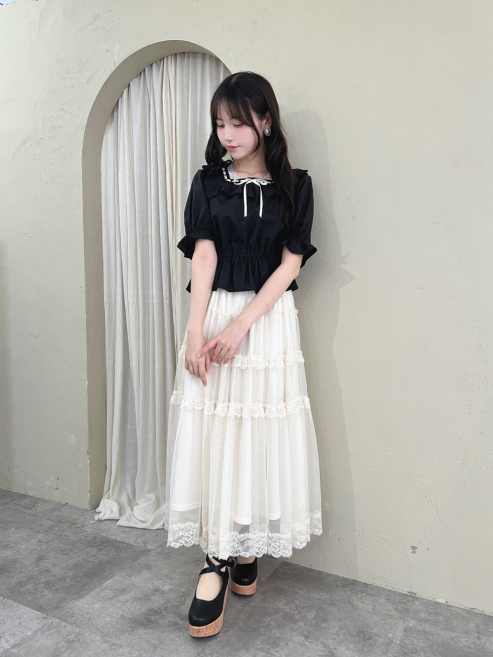 ブラック系のパンプス、ホワイト系のスカート、ブラック系のシャツ/ブラウスを着用したレディースの夏コーディネートの1枚目の写真