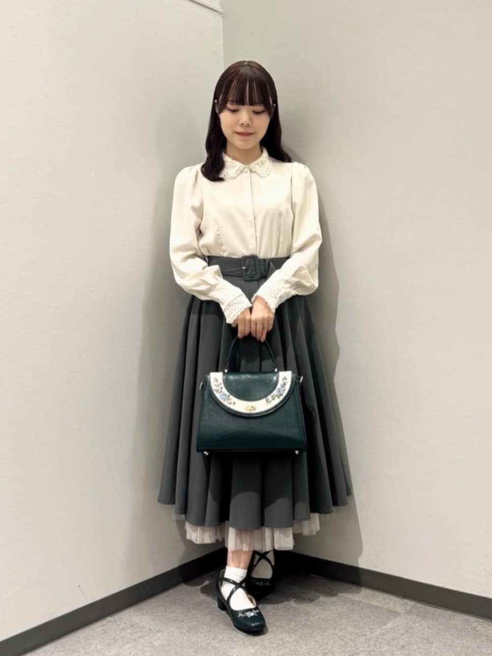 グリーン系のスカート、ピンク系のシャツ/ブラウス、ブルー系のハンドバッグを着用したレディースの秋コーディネートの1枚目の写真