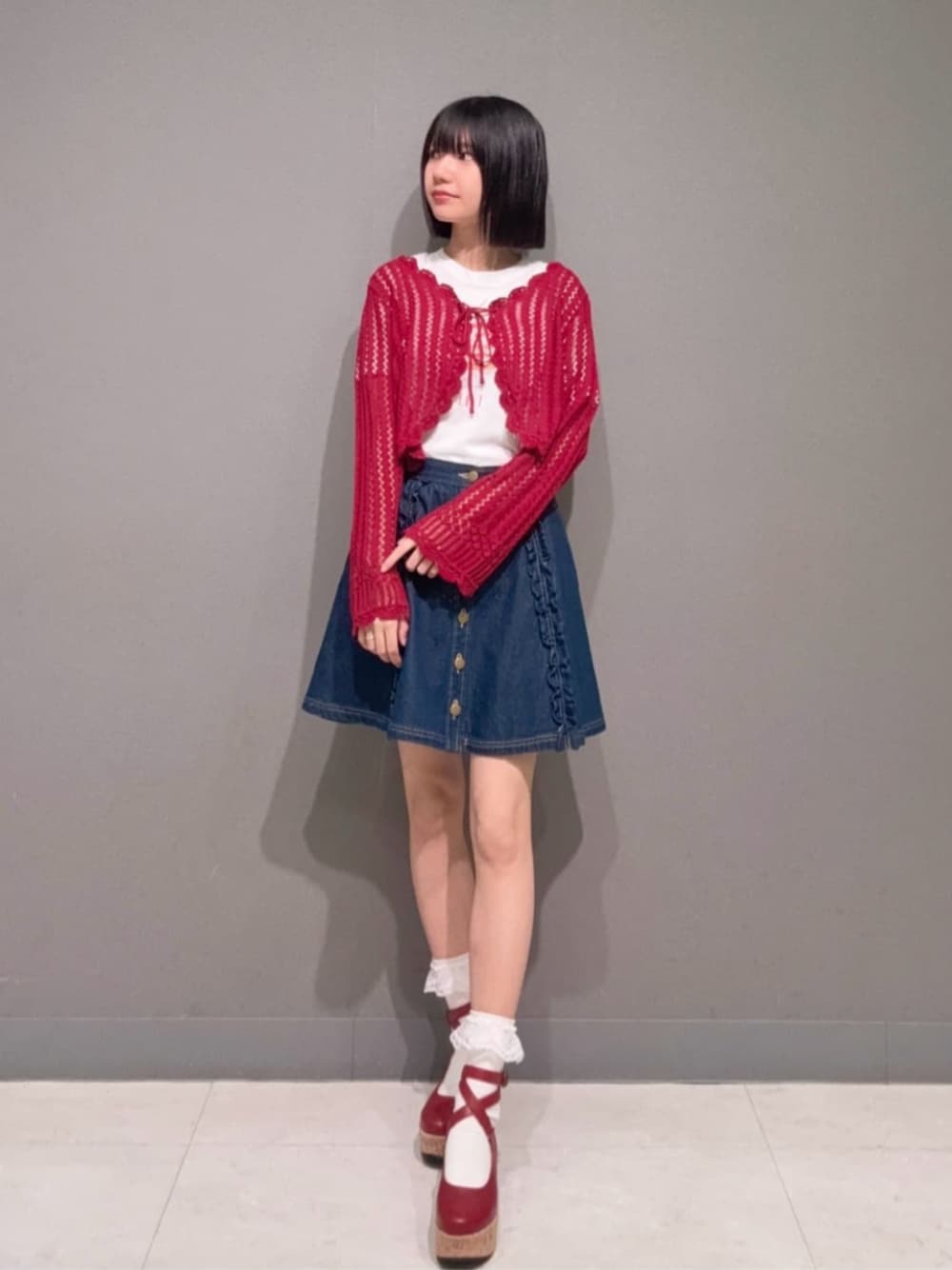 レッド系のパンプス、ブルー系のデニムスカート、レッド系のカーディガン/ボレロを着用したレディースの夏コーディネートの1枚目の写真
