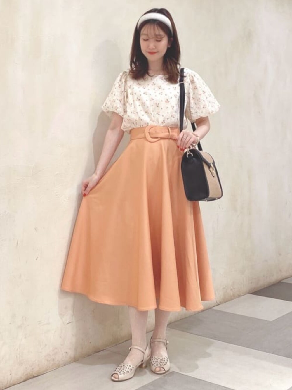 ブラック系のハンドバッグ、オレンジ系のシャツ/ブラウス、オレンジ系のスカートを着用したレディースの春コーディネートの1枚目の写真