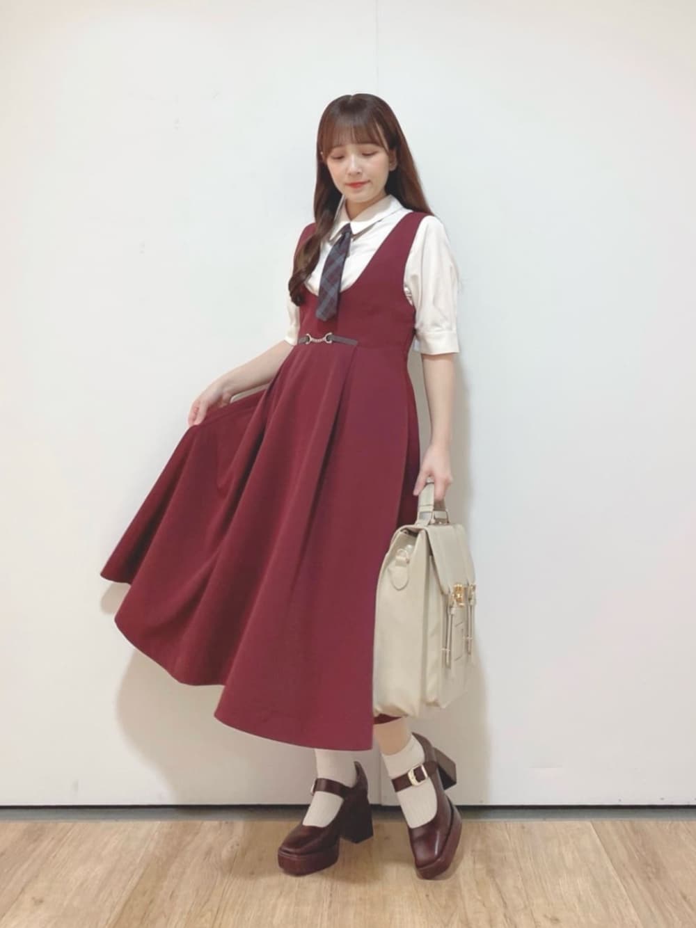 ベージュ系のハンドバッグ、ブラウン系のパンプス、レッド系のジャンパースカートを着用したレディースの夏コーディネートの1枚目の写真