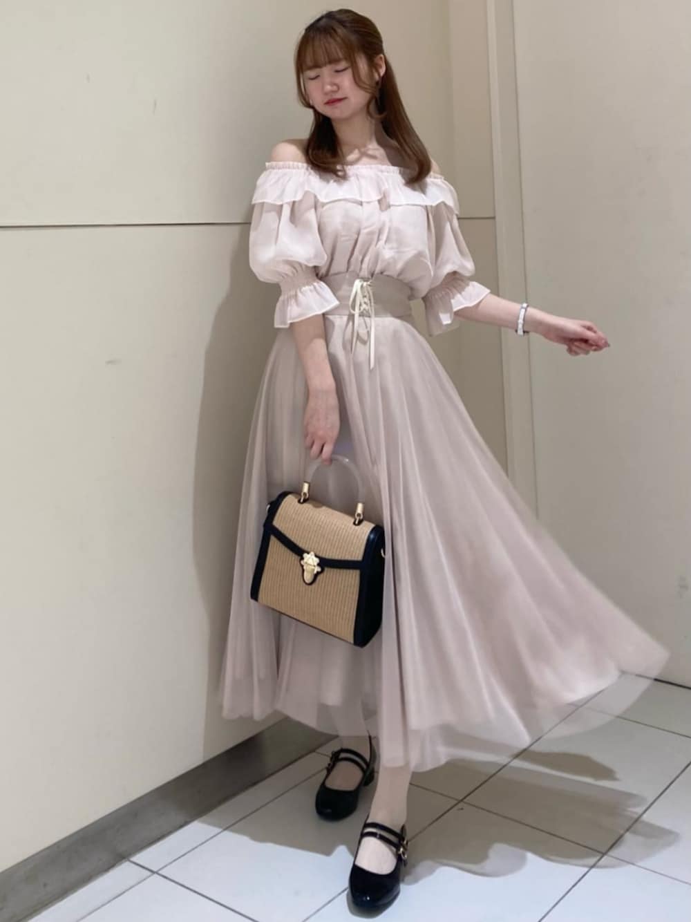 ホワイト系のスカート、ブラック系のハンドバッグ、ブラック系のパンプスを着用したレディースの春コーディネートの1枚目の写真