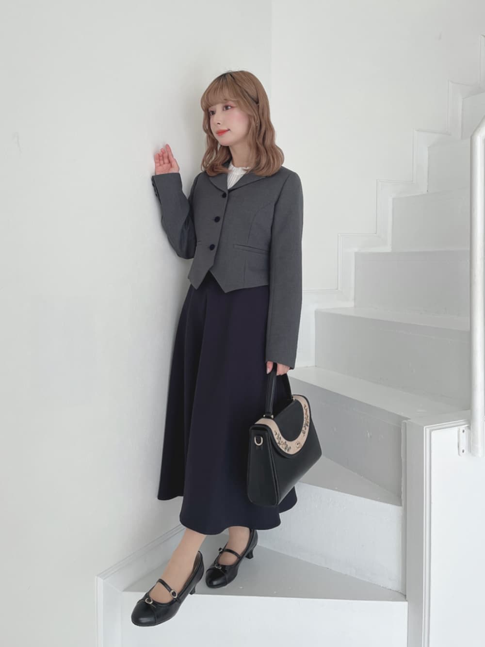 ブラック系のパンプス、ブラック系のハンドバッグ、グレー系のテーラードジャケットを着用したレディースの秋コーディネートの1枚目の写真