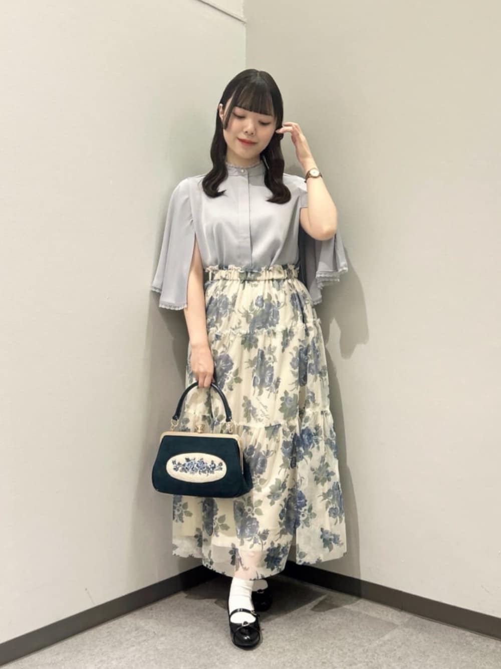 グレー系のシャツ/ブラウス、ブルー系のスカート、ブルー系のハンドバッグを着用したレディースの夏コーディネートの1枚目の写真