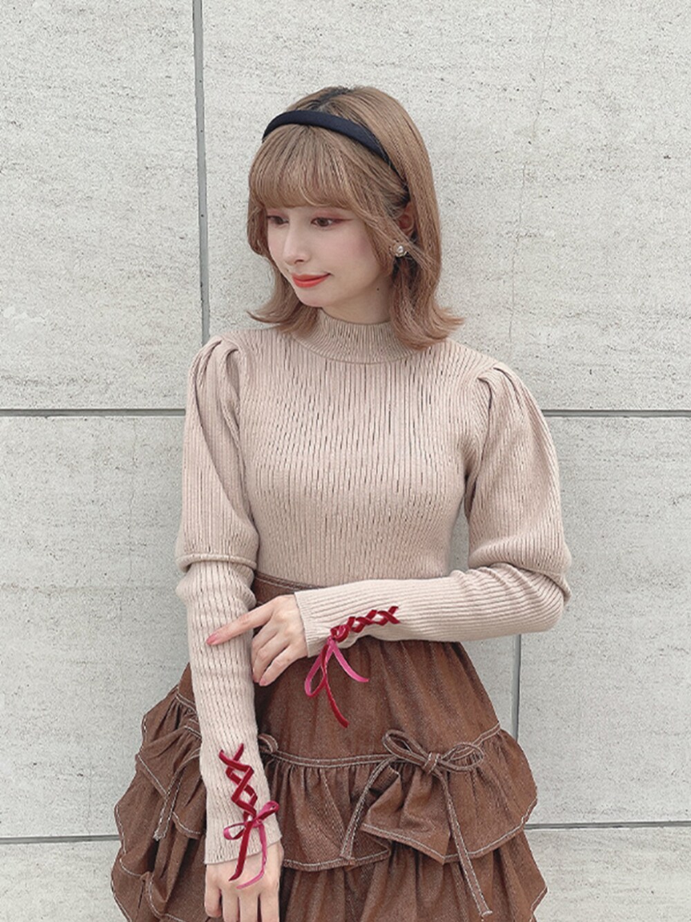 ブラウン系のスカート、ベージュ系のニット/セーター、ブラック系のカチューシャを着用したレディースの秋コーディネートの1枚目の写真