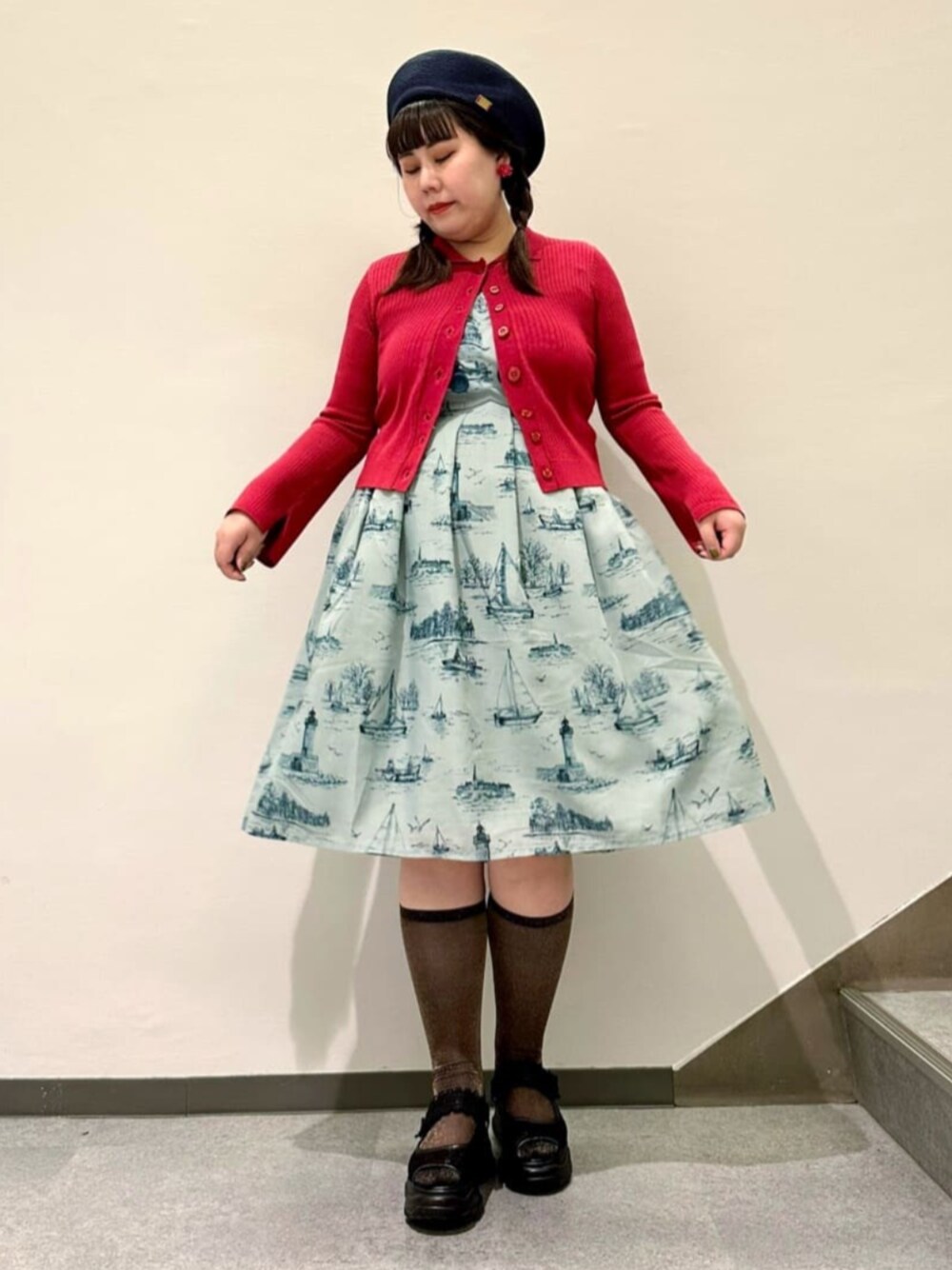 ブルー系のワンピース、レッド系のカーディガン/ボレロ、ブラック系のスニーカーを着用したレディースの春コーディネートの1枚目の写真