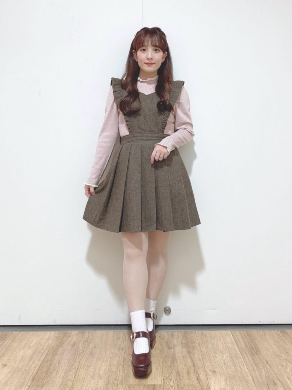 ブラウン系のパンプス、ブラウン系のジャンパースカート、ピンク系のニット/セーターを着用したレディースの秋コーディネートの1枚目の写真
