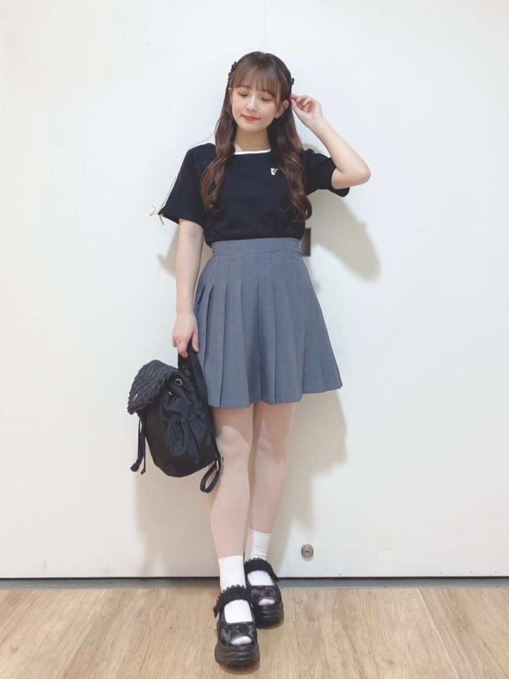 ブラック系のバックパック/リュック、グレー系のスカート、ブラック系のスニーカーを着用したレディースの夏コーディネートの1枚目の写真