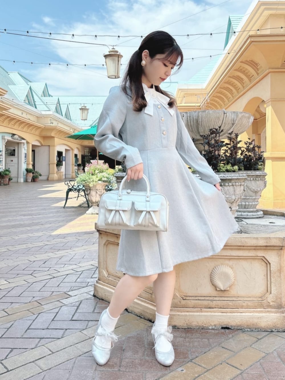 シルバー系のハンドバッグ、シルバー系のパンプス、グレー系のワンピースを着用したレディースの秋コーディネートの1枚目の写真