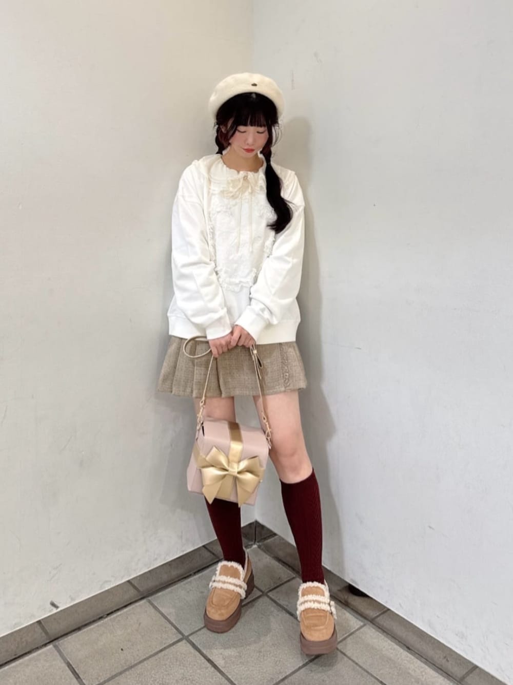 ホワイト系のスウェット、ピンク系のショルダーバッグ、ベージュ系のスカートを着用したレディースの冬コーディネートの1枚目の写真