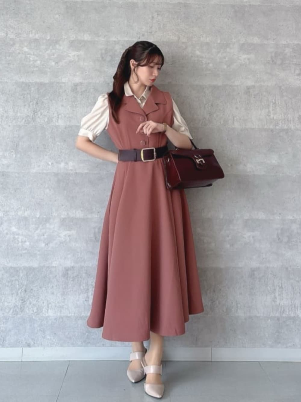 レッド系のハンドバッグ、レッド系のワンピース、ベージュ系のシャツ/ブラウスを着用したレディースの夏コーディネートの1枚目の写真