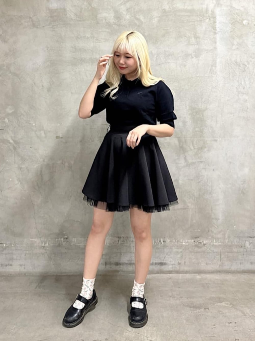 ブラック系のスカート、ブラック系のポロシャツを着用したレディースの春コーディネートの1枚目の写真