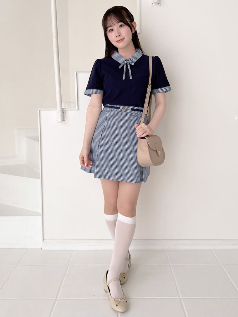 ベージュ系のバレエシューズ、ピンク系のショルダーバッグ、ブルー系のスカートを着用したレディースの春コーディネートの1枚目の写真