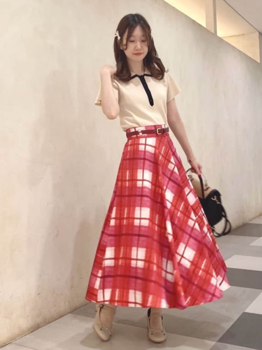 ブラック系のハンドバッグ、レッド系のスカート、ホワイト系のポロシャツを着用したレディースの春コーディネートの1枚目の写真