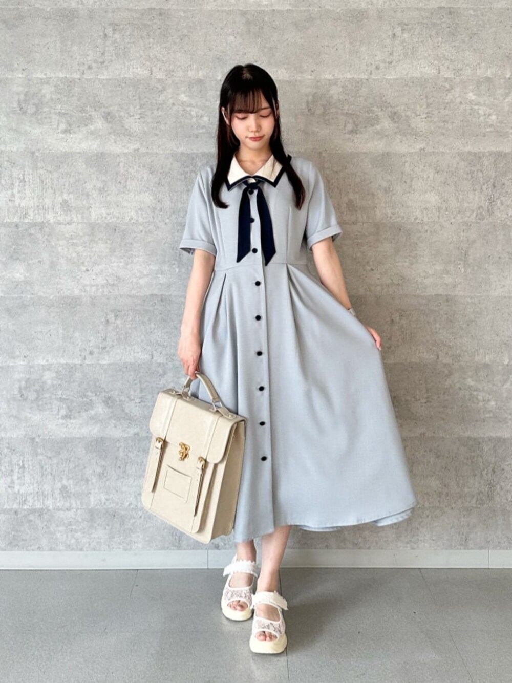 ベージュ系のハンドバッグ、ホワイト系のサンダル、グレー系のワンピースを着用したレディースの夏コーディネートの1枚目の写真
