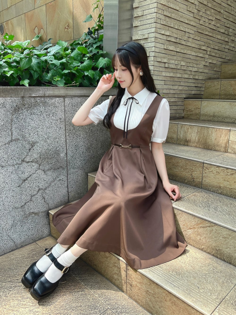 ホワイト系のシャツ/ブラウス、ブラック系のパンプス、ブラウン系のジャンパースカートを着用したレディースの夏コーディネートの1枚目の写真