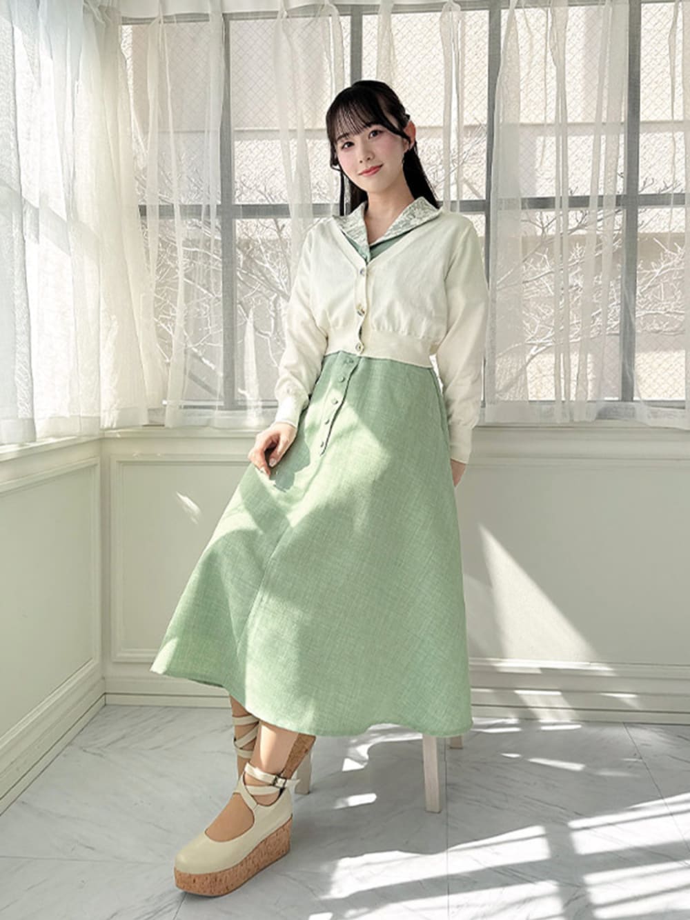 ホワイト系のパンプス、グリーン系のワンピース、ホワイト系のカーディガン/ボレロを着用したレディースの春コーディネートの1枚目の写真