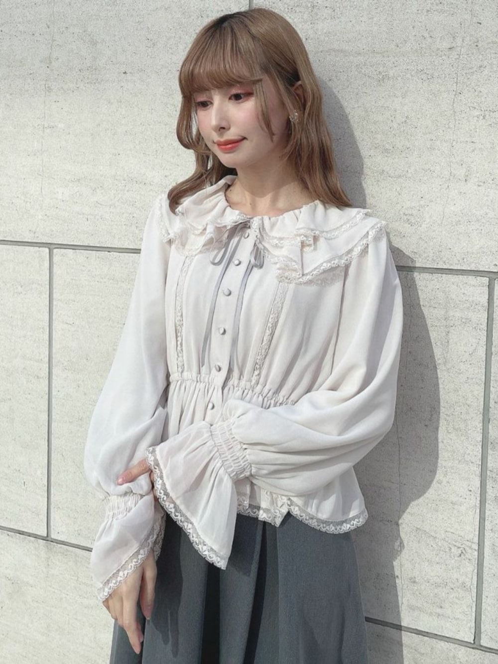 ブラック系のパンプス、ピンク系のシャツ/ブラウス、グレー系のスカートを着用したレディースの冬コーディネートの1枚目の写真