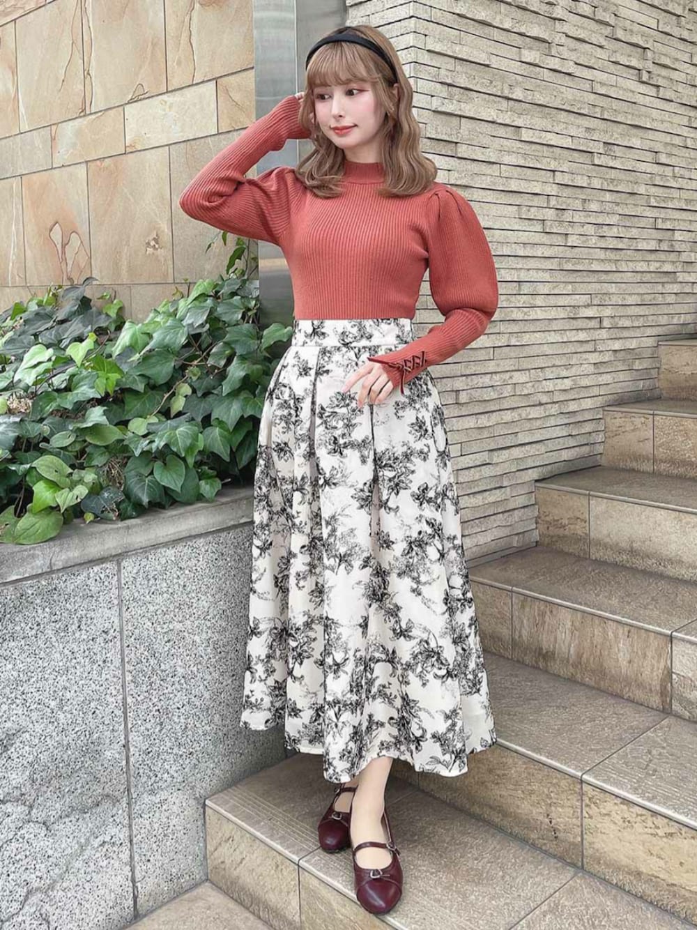 レッド系のパンプス、オレンジ系のニット/セーター、ホワイト系のスカートを着用したレディースの冬コーディネートの1枚目の写真