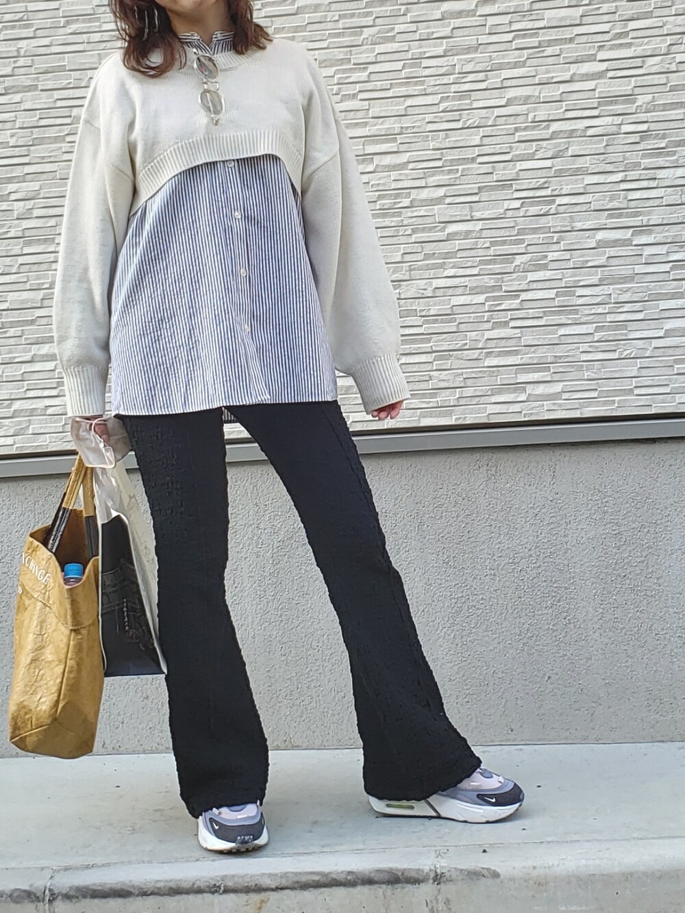 ホワイト系のニット/セーター、グレー系のシャツ/ブラウス、ベージュ系のトートバッグを着用したレディースの春コーディネートの3枚目の写真