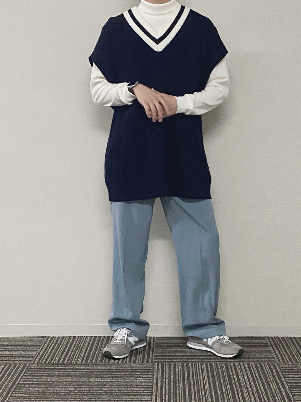 ブルー系のベスト、ホワイト系のニット/セーター、グレー系のスラックスを着用したメンズの春コーディネートの1枚目の写真