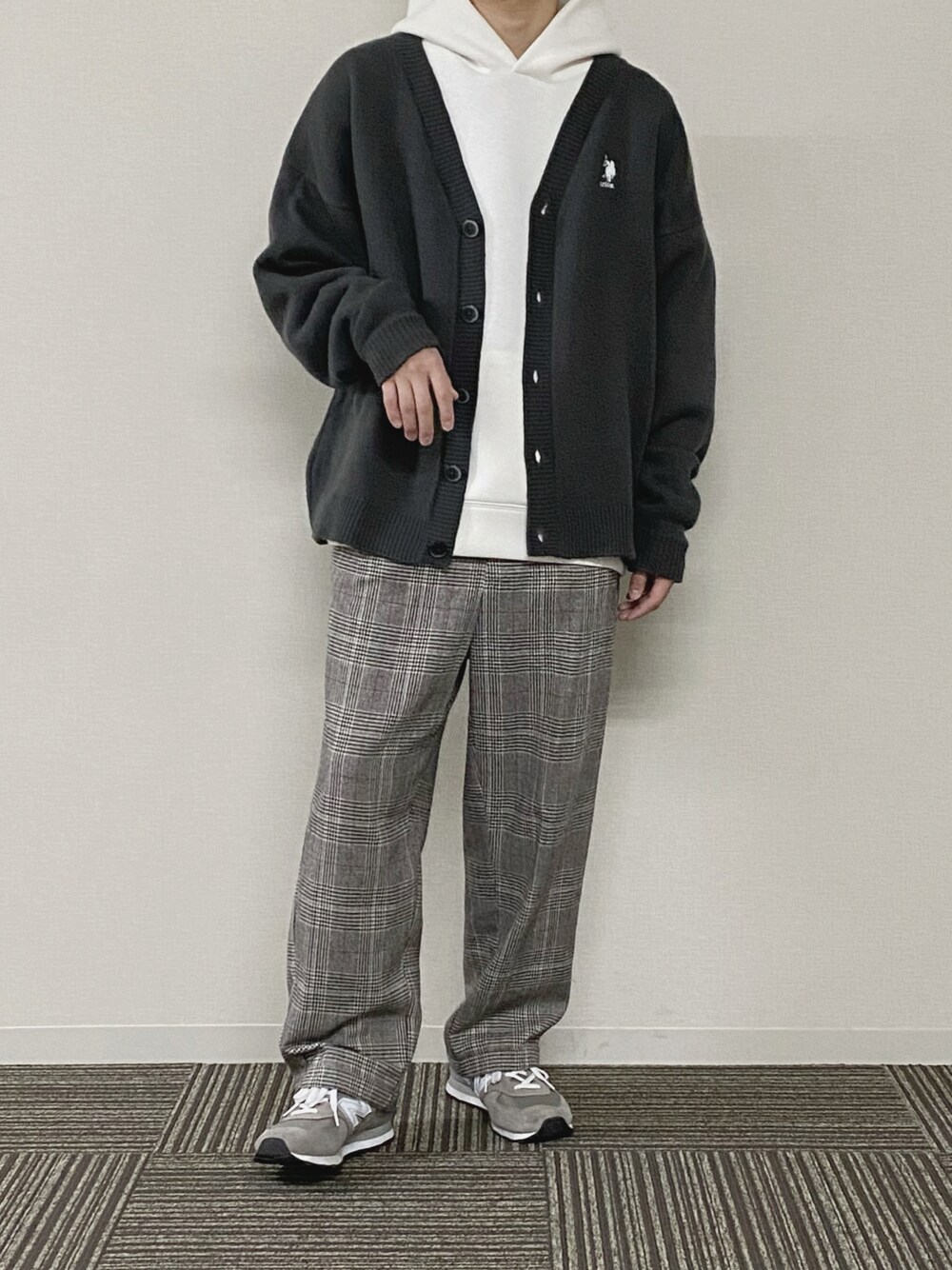 ホワイト系のパーカー、グレー系のカーディガン/ボレロ、ブラウン系のスラックスを着用したメンズの春コーディネートの1枚目の写真