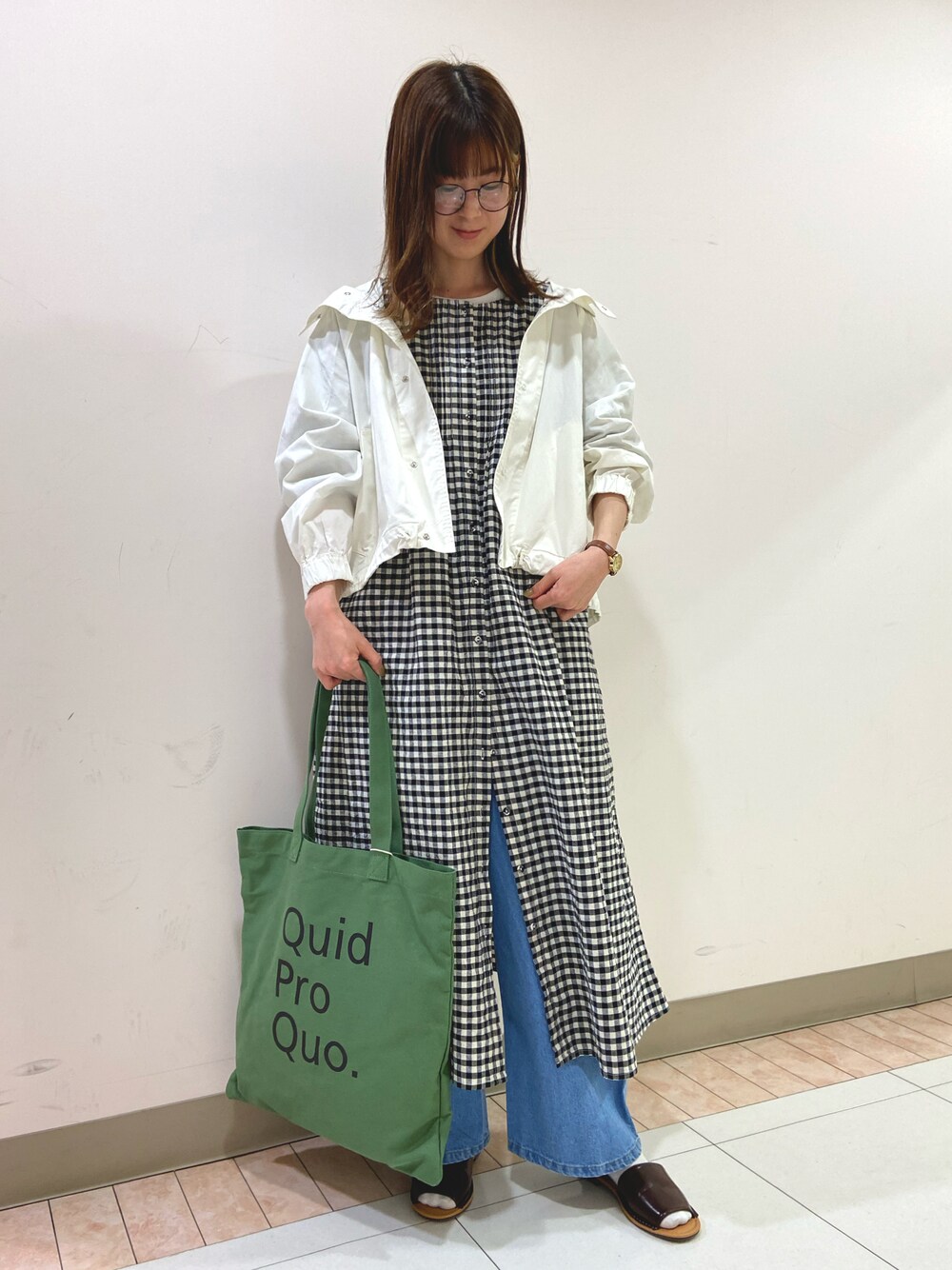 ホワイト系のマウンテンパーカー、ブラック系のワンピース、グリーン系のトートバッグを着用したレディースの春コーディネートの1枚目の写真