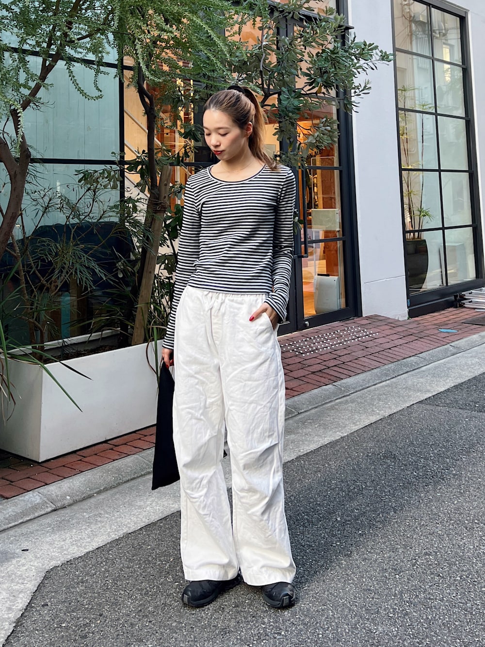 グレー系のTシャツ/カットソー、ホワイト系のチノパンツ、ブラック系のスニーカーを着用したレディースの秋コーディネートの1枚目の写真