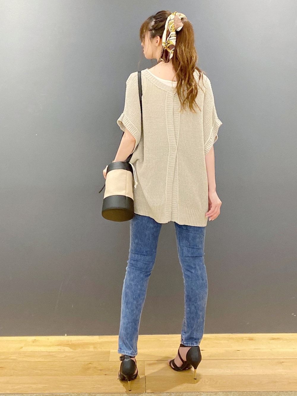 グリーン系のニット/セーター、ブラック系のショルダーバッグ、ブルー系のデニムパンツを着用したレディースの夏コーディネートの1枚目の写真