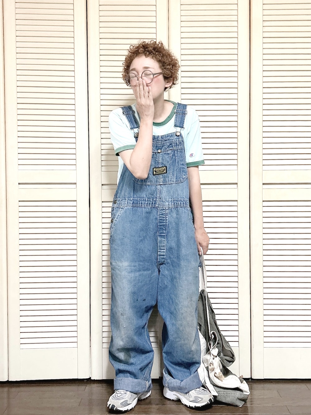 グレー系のスニーカー、ブルー系のサロペット/オーバーオール、グリーン系のショルダーバッグを着用したレディースの春コーディネートの1枚目の写真