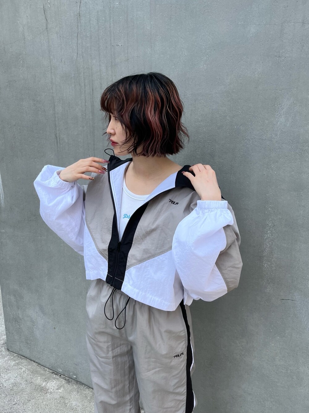 グレー系のブルゾン、グレー系のその他パンツ、ホワイト系のタンクトップを着用したレディースの春コーディネートの2枚目の写真