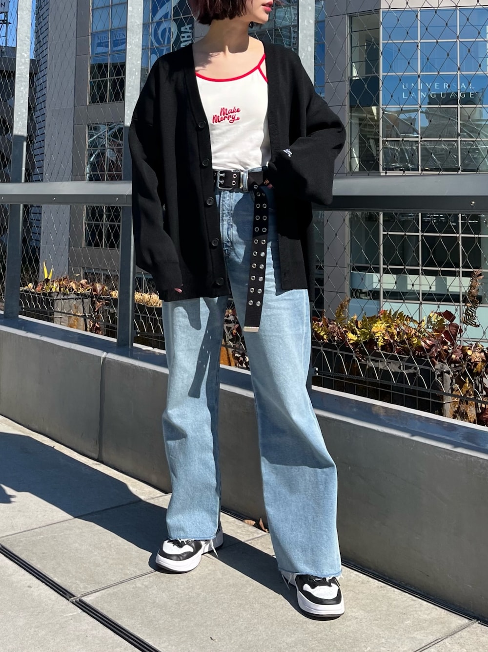 ホワイト系のキャミソール、ブラック系のカーディガン/ボレロ、ブルー系のデニムパンツを着用したレディースの春コーディネートの2枚目の写真