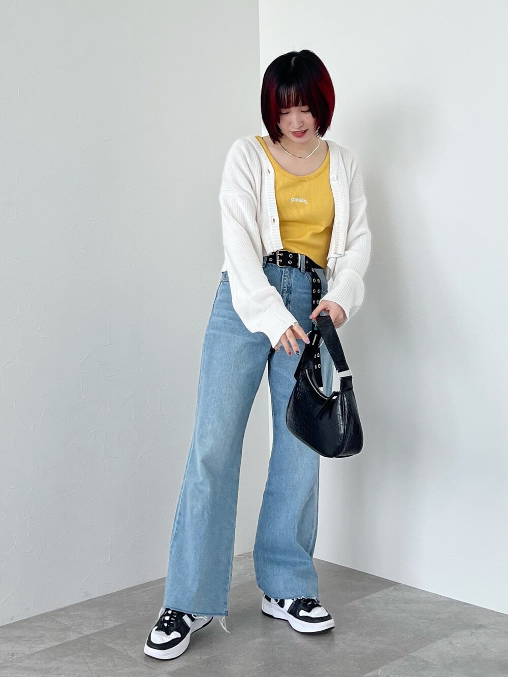 イエロー系のタンクトップ、ホワイト系のカーディガン/ボレロ、ブルー系のデニムパンツを着用したレディースの春コーディネートの4枚目の写真