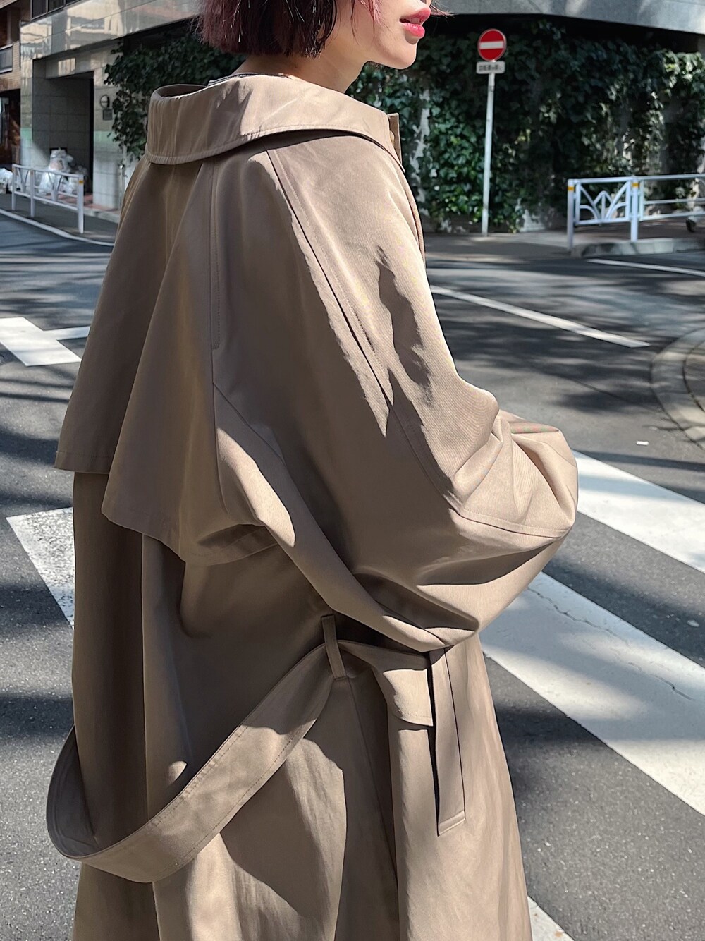 ホワイト系のTシャツ/カットソー、ベージュ系のステンカラーコート、ブラック系のバッグを着用したレディースの春コーディネートの3枚目の写真