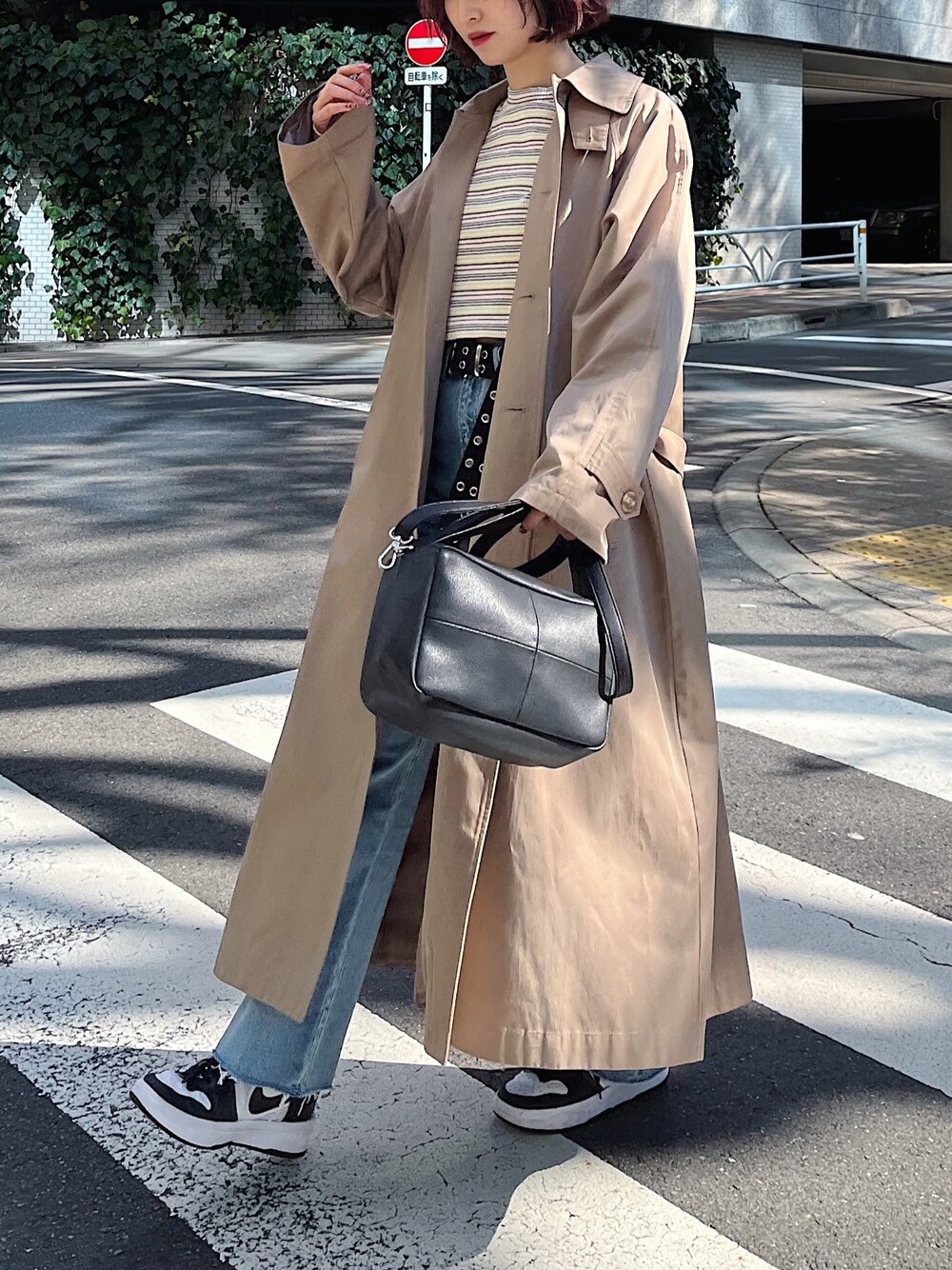 ホワイト系のTシャツ/カットソー、ベージュ系のステンカラーコート、ブラック系のバッグを着用したレディースの春コーディネートの2枚目の写真