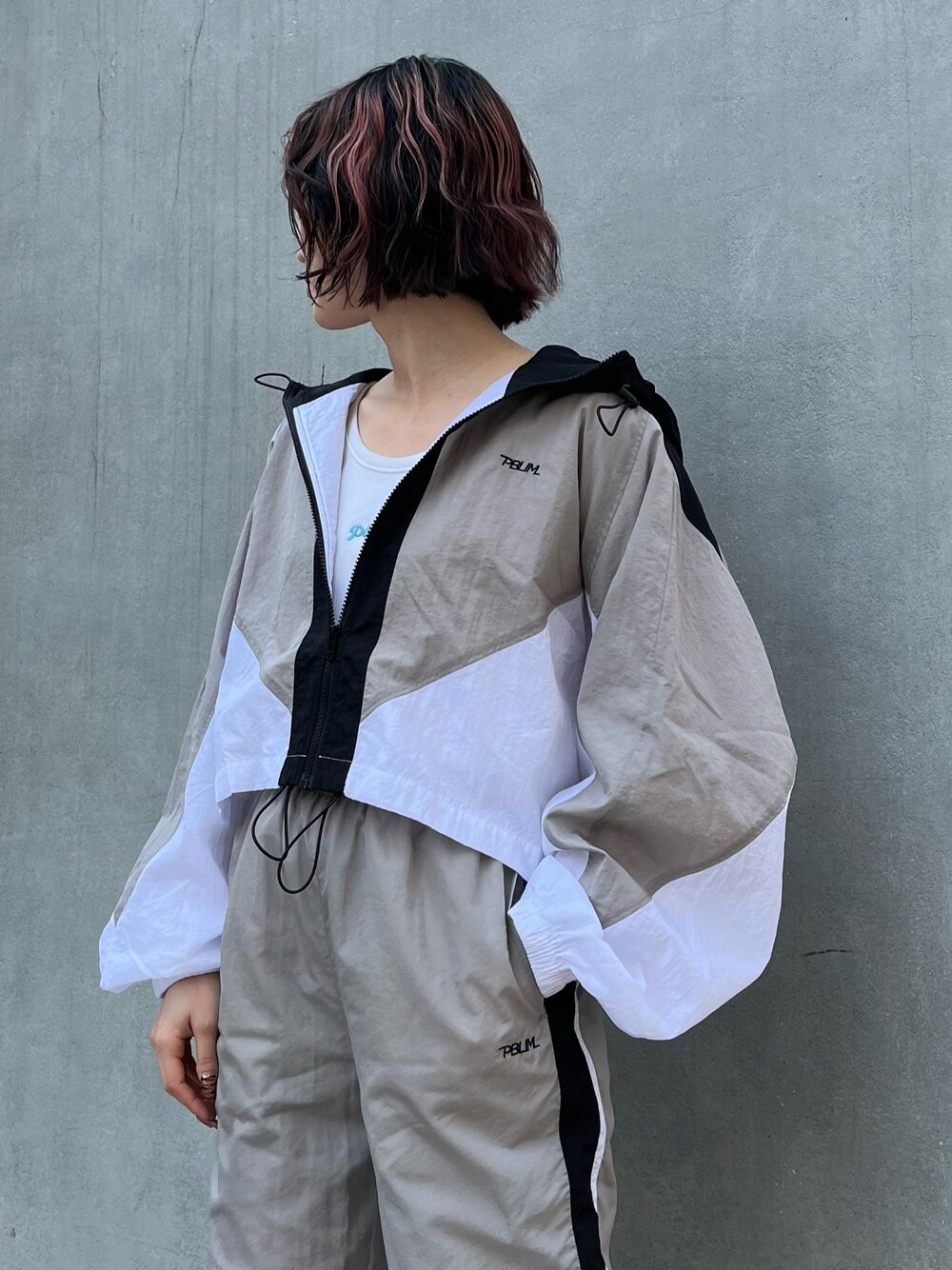 グレー系のブルゾン、グレー系のその他パンツ、ホワイト系のタンクトップを着用したレディースの春コーディネートの3枚目の写真
