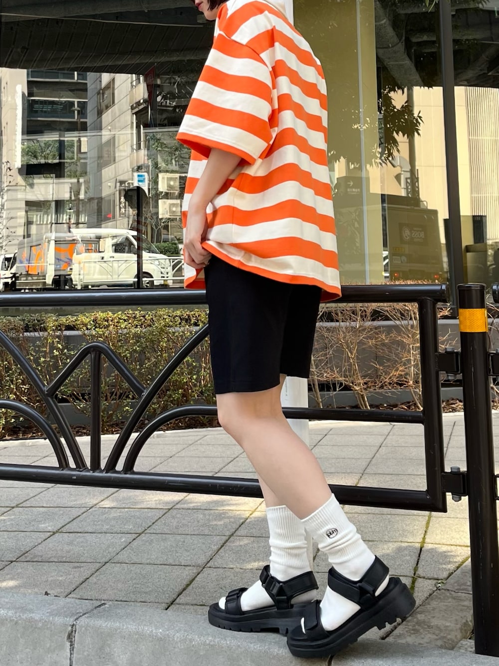 オレンジ系のポロシャツ、ブラック系のその他パンツを着用したレディースの春コーディネートの4枚目の写真