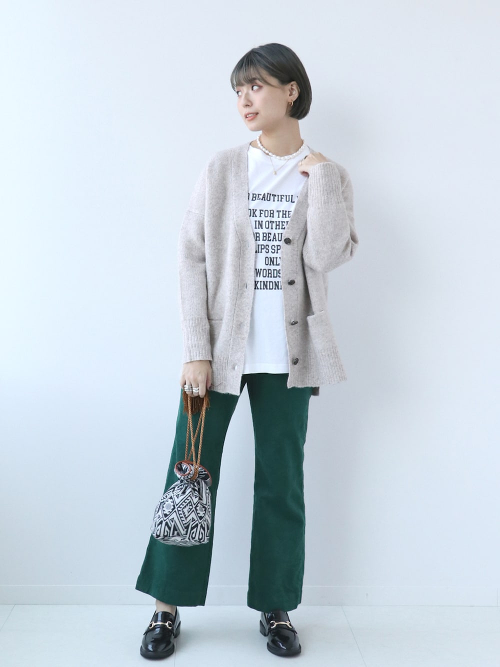 ベージュ系のカーディガン/ボレロ、ホワイト系のTシャツ/カットソー、ブラック系のショルダーバッグを着用したレディースの秋コーディネートの1枚目の写真