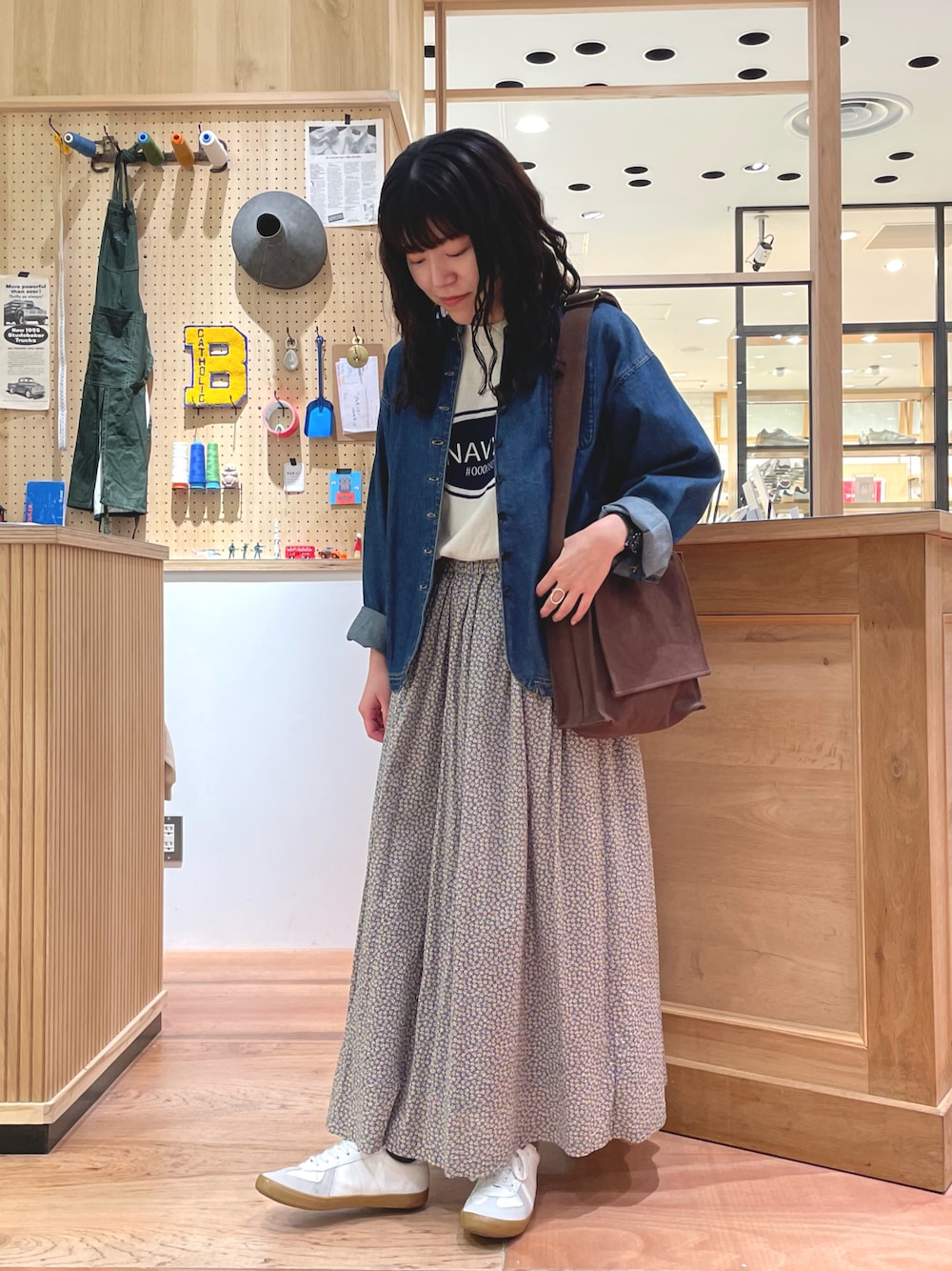 イエロー系のスカート、ブラウン系のショルダーバッグ、ブルー系のデニムジャケットを着用したレディースの春コーディネートの1枚目の写真