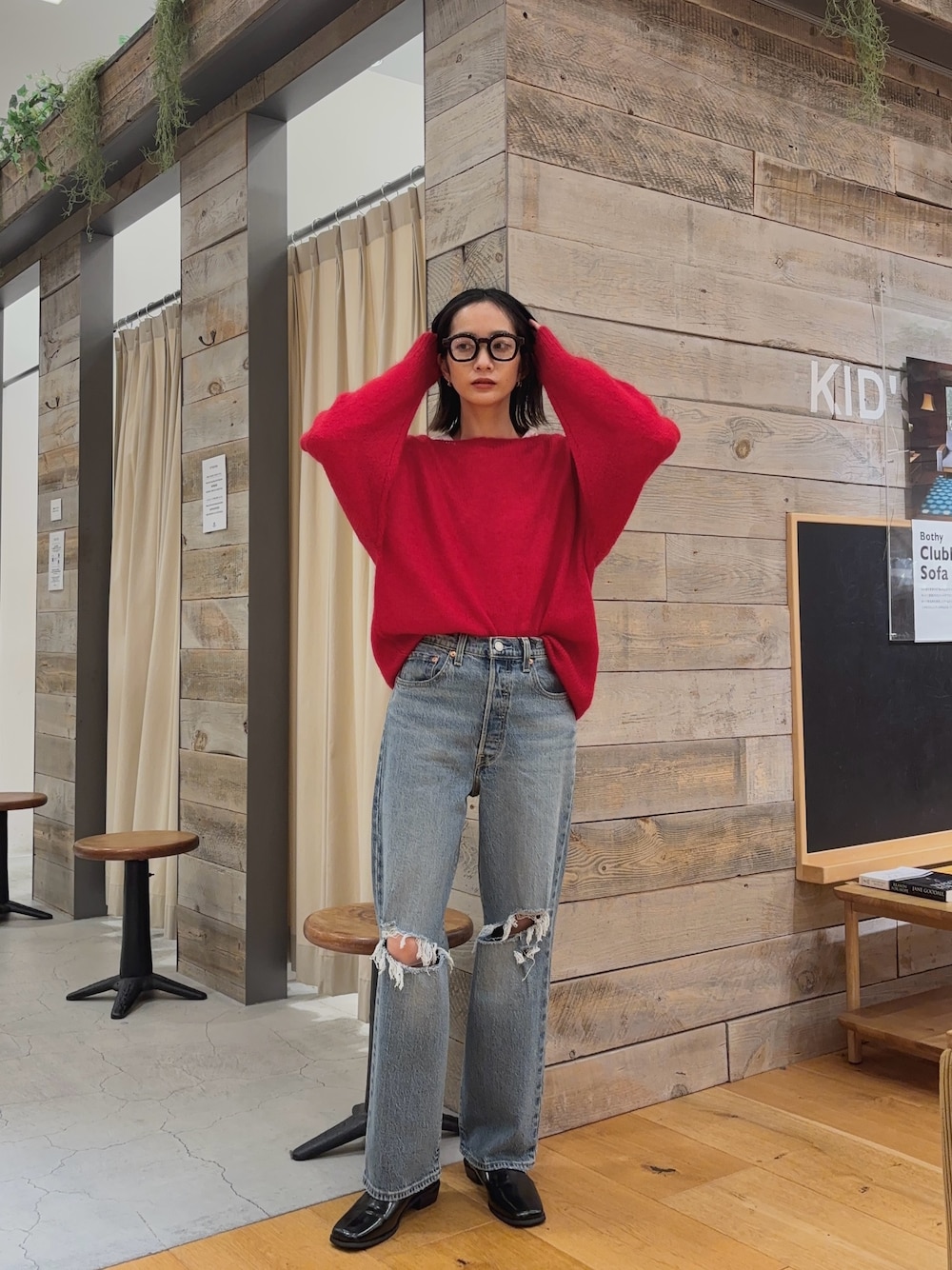 レッド系のニット/セーター、ブルー系のデニムパンツ、ブラック系のシューズを着用したレディースの秋コーディネートの1枚目の写真