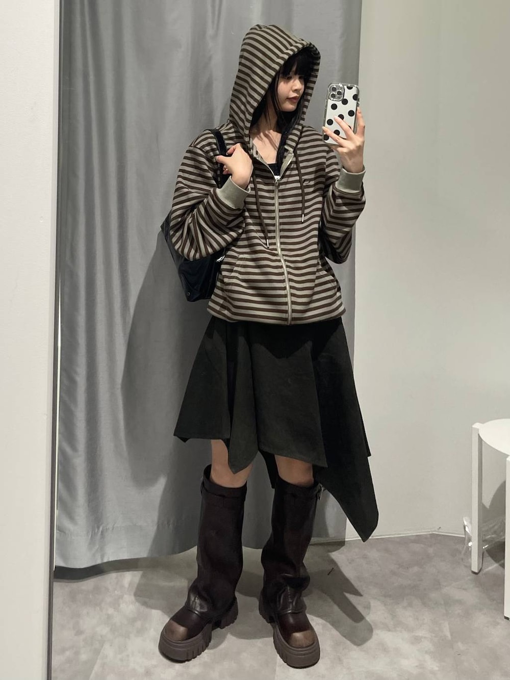 ブラウン系のブーツ、グリーン系のスカート、ブラック系のハンドバッグを着用したレディースの秋コーディネートの1枚目の写真