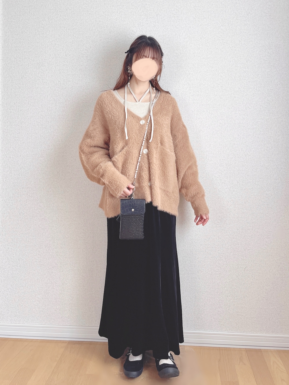 ベージュ系のTシャツ/カットソー、オレンジ系のカーディガン/ボレロ、ブラック系のスカートを着用したレディースの冬コーディネートの1枚目の写真