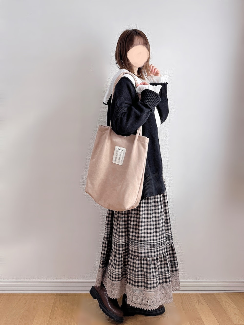 ブラック系のニット/セーター、ブラウン系のブーツ、ベージュ系のトートバッグを着用したレディースの冬コーディネートの1枚目の写真