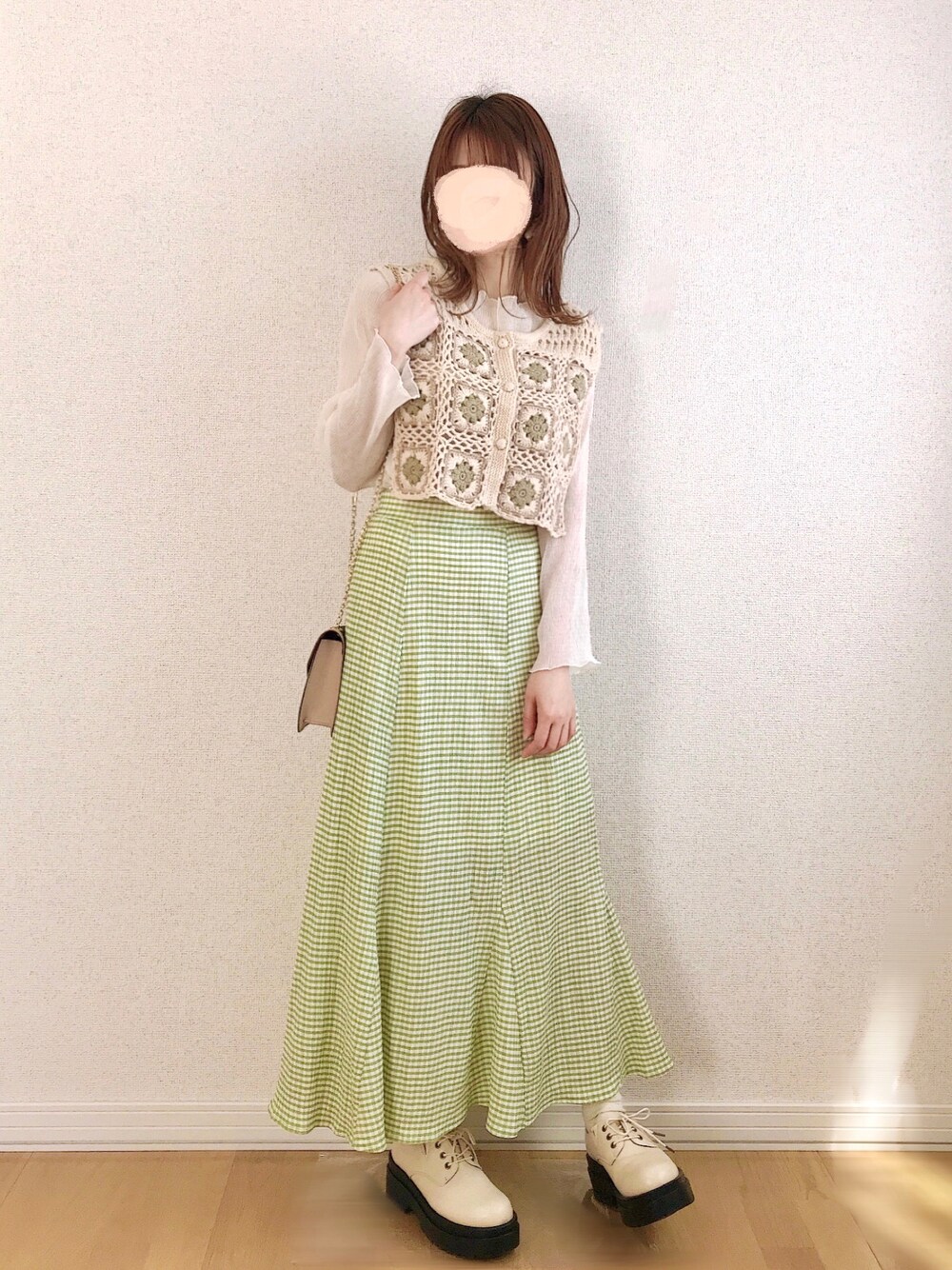 グリーン系のスカート、ホワイト系のベスト、ホワイト系のTシャツ/カットソーを着用したレディースの春コーディネートの1枚目の写真